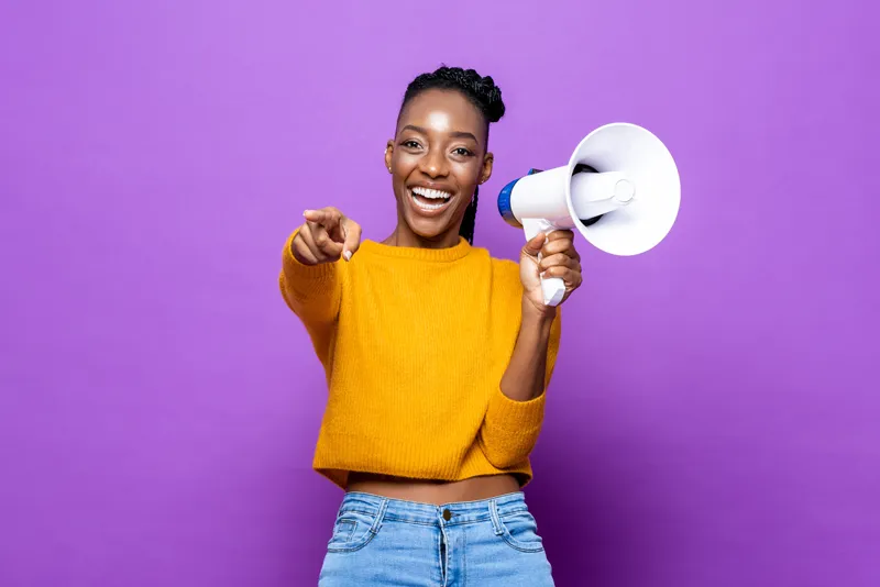 a woman with a megaphone smiling and pointing at something