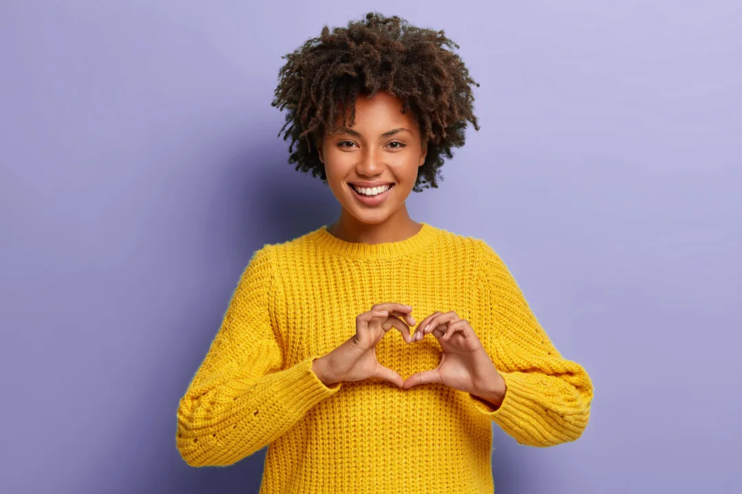a woman making a heart with her hands.