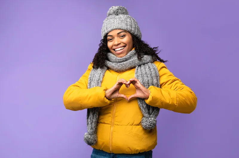 a lady smiling wearing a winter jacket with a hear sign