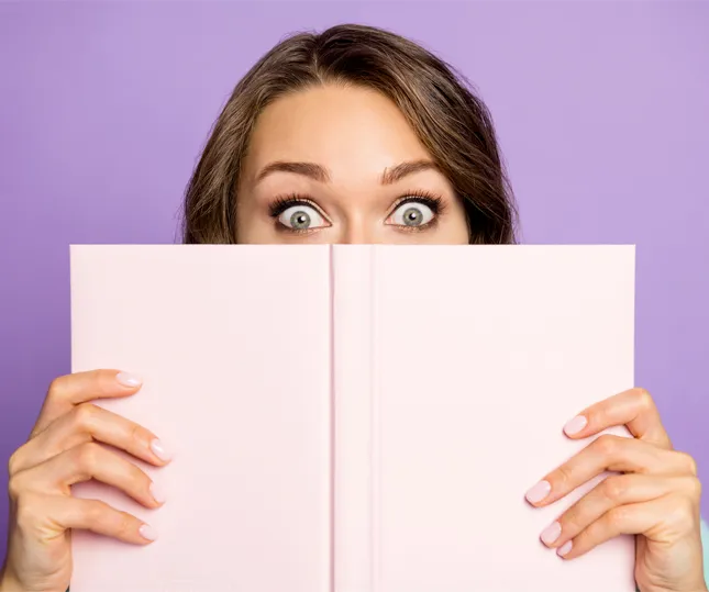 a woman holding up a branded notebook close to her eyes