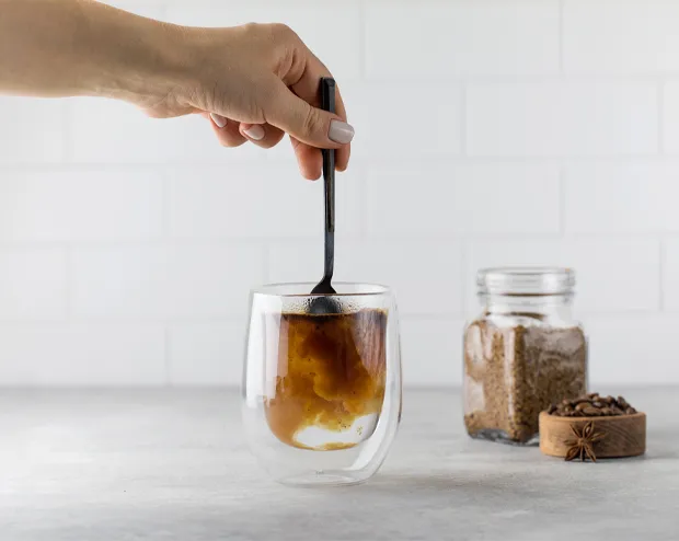 glass cup with a hot drink being stirred