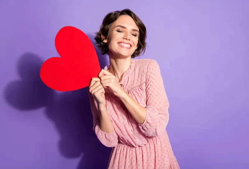 a lady smiling with a heart shaped paper