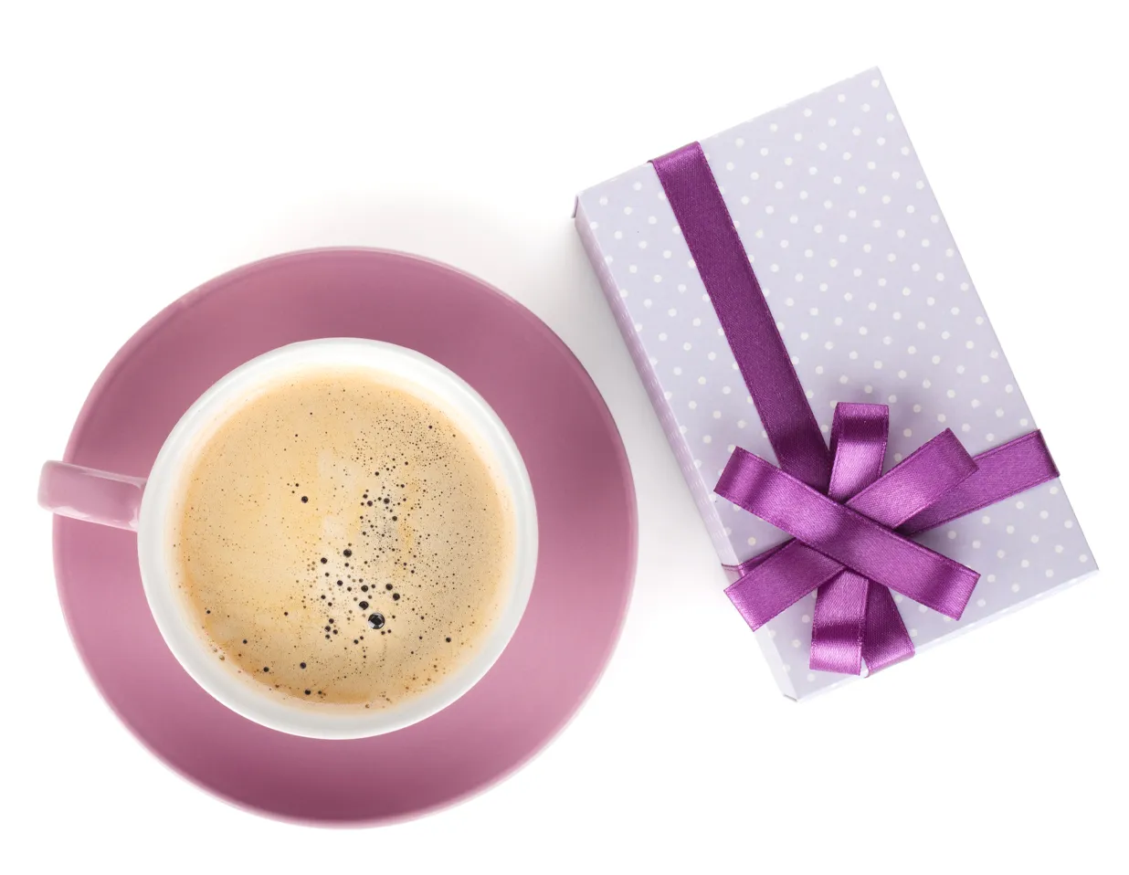 coffee in a cup next to a gift box wrapped in a ribbon