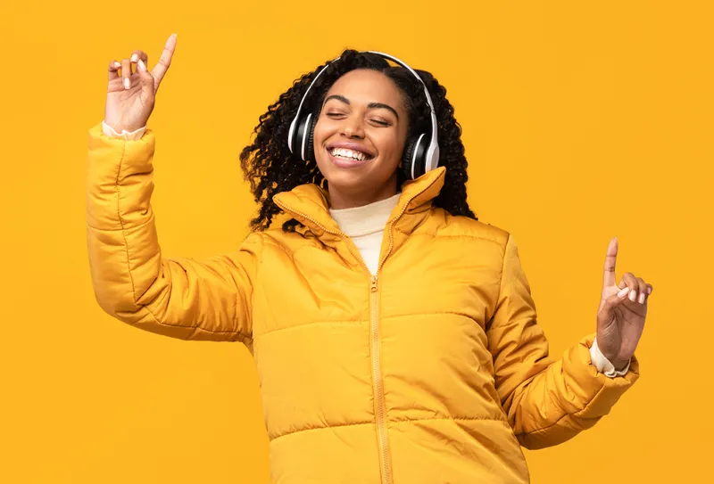 a women with headphones and a branded puffer jacket, listening to music