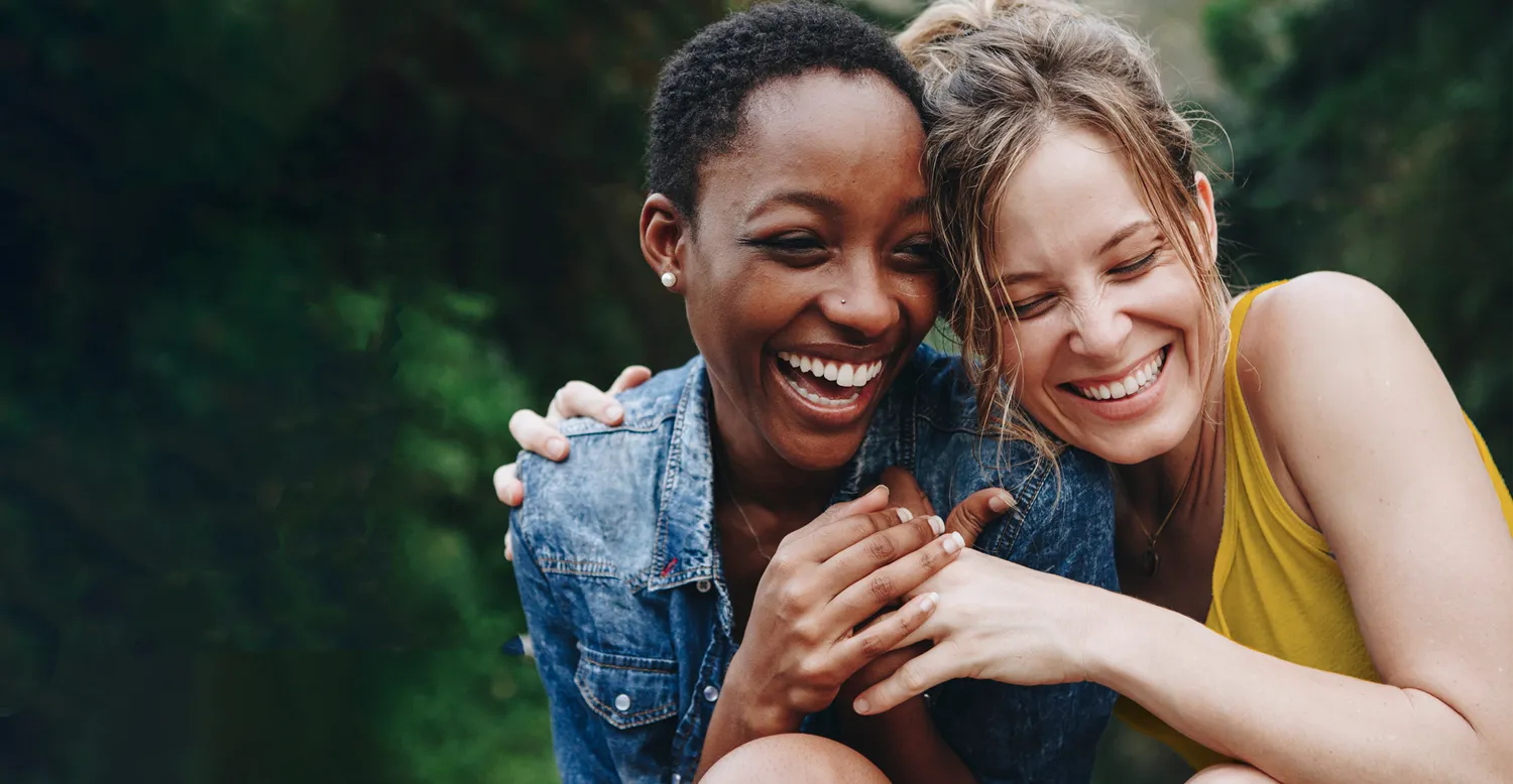 Joyful pair of women posing with beaming smiles for personalized calendars