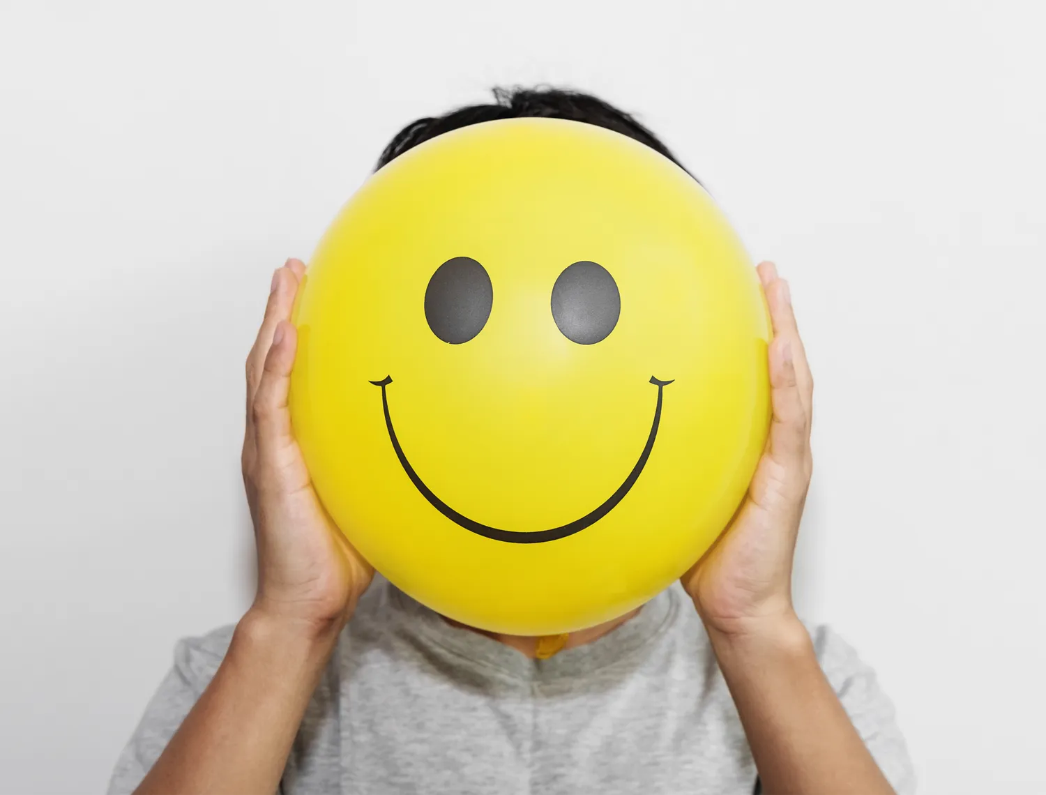a person holding a smiley face ballon up