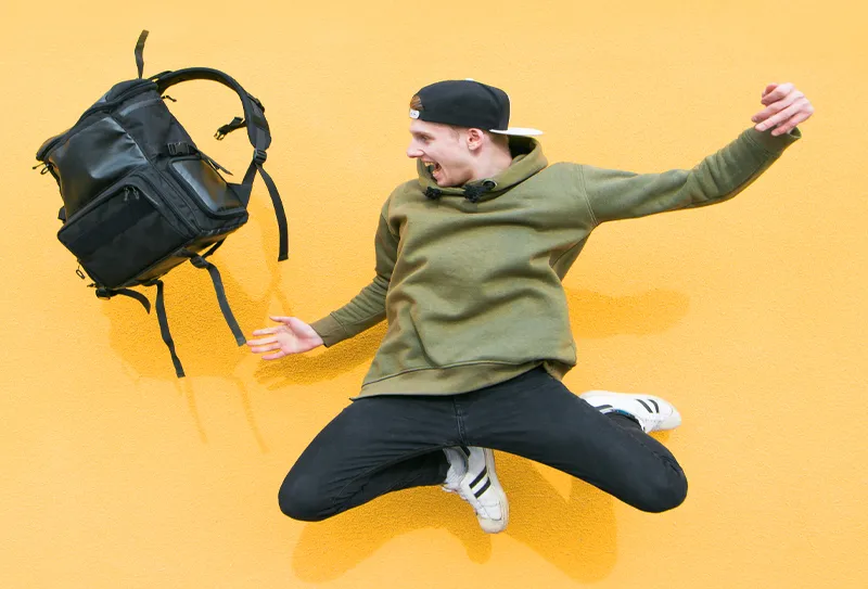 a young man jumping the air with leisure bags