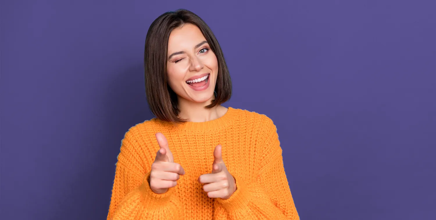 a woman pointing straight ahead with a smile on a her face.